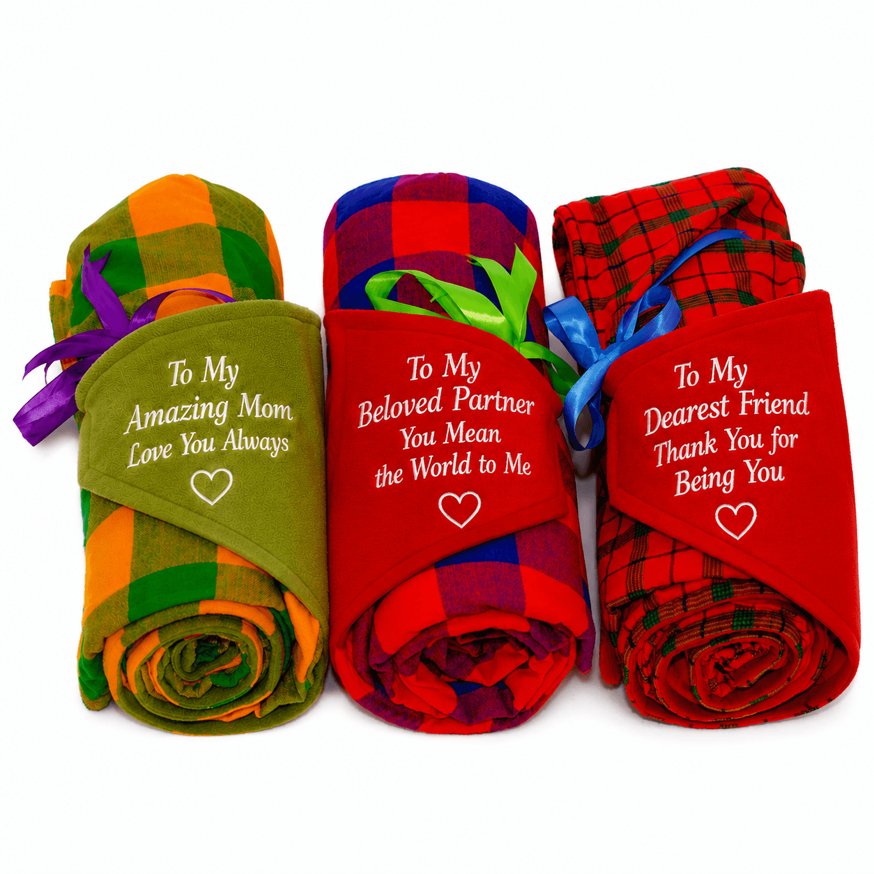 Three personalised Maasai fleece blankets with messages for Mum, a partner and a friend, heart details and colourful ribbons.