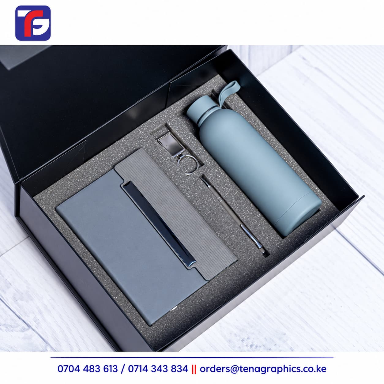 Grey E128 end of year corporate gift set with notebook, light grey bottle, pen and metal keyholder in a black box