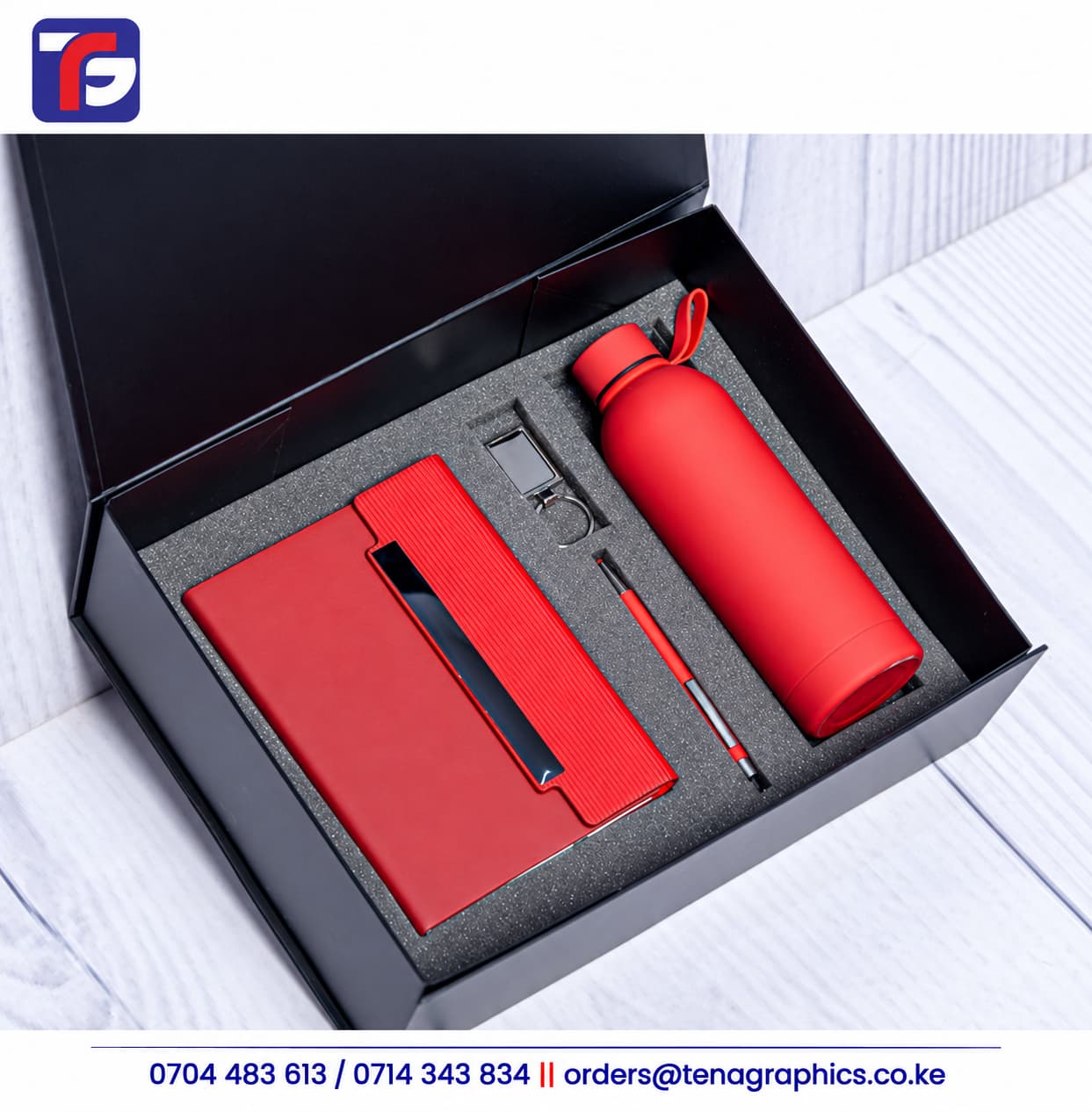 Red E128 end of year corporate gift set with notebook, bottle, pen and metal keyholder in a black presentation box