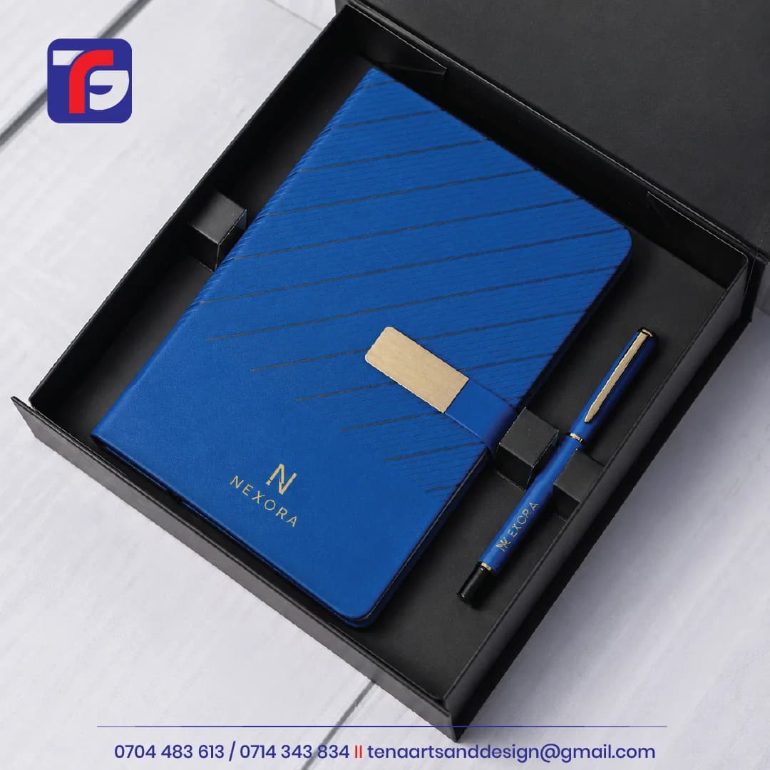 Blue branded notebook and pen set with gold-coloured Nexora logos, a notebook closure strap and a black presentation box.