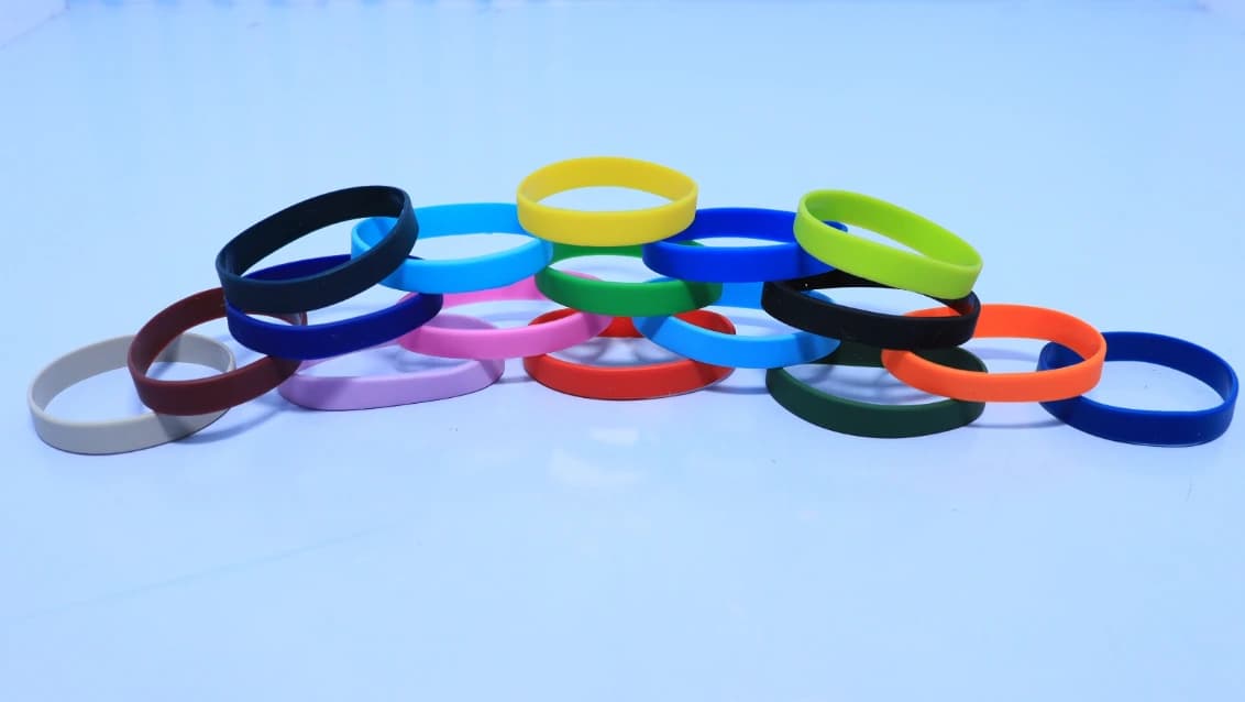 Assorted coloured adult loop wristbands arranged on a light background