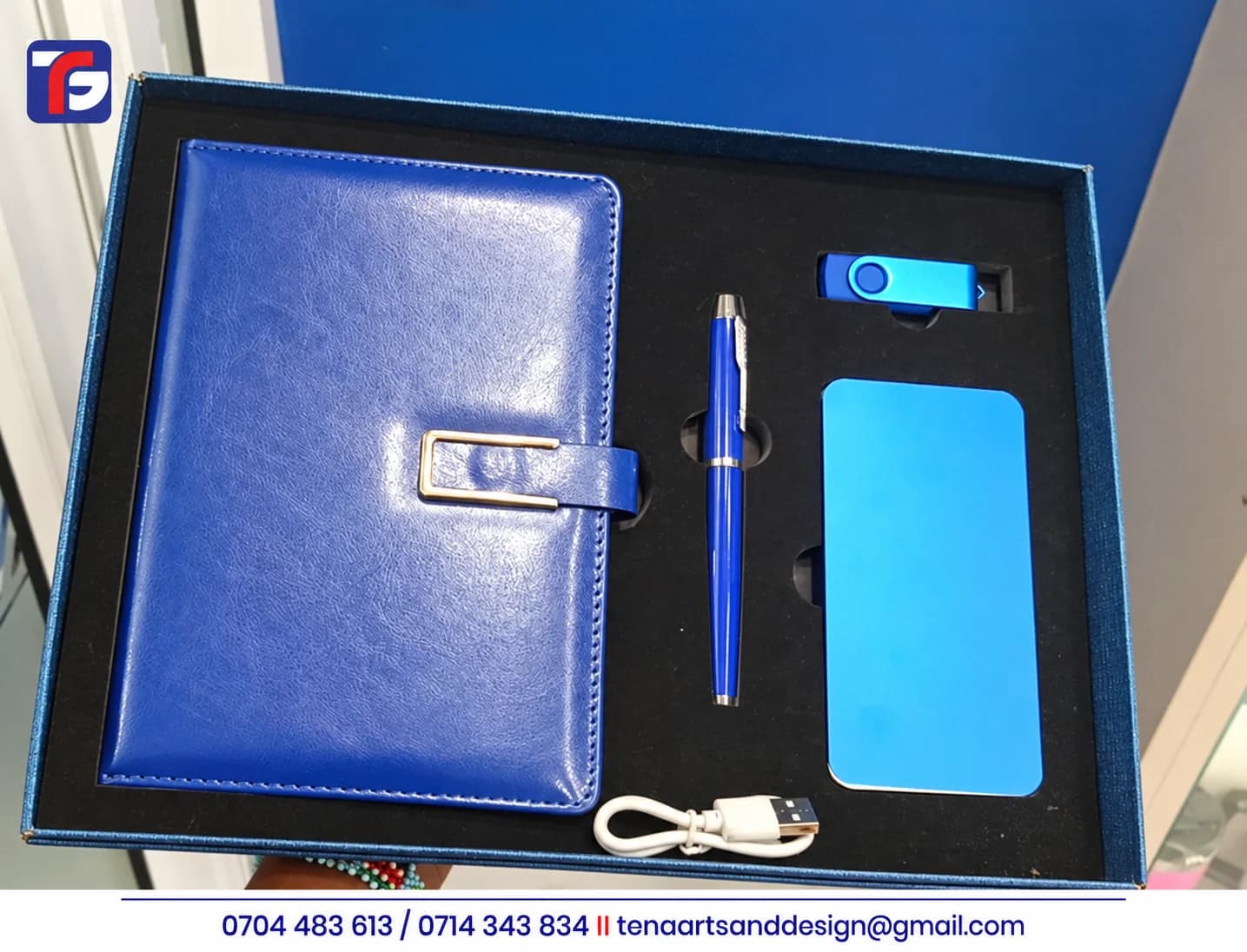 Blue executive notebook and USB gift set with a pen, power bank, swivel flash disk and white cable in an open presentation box