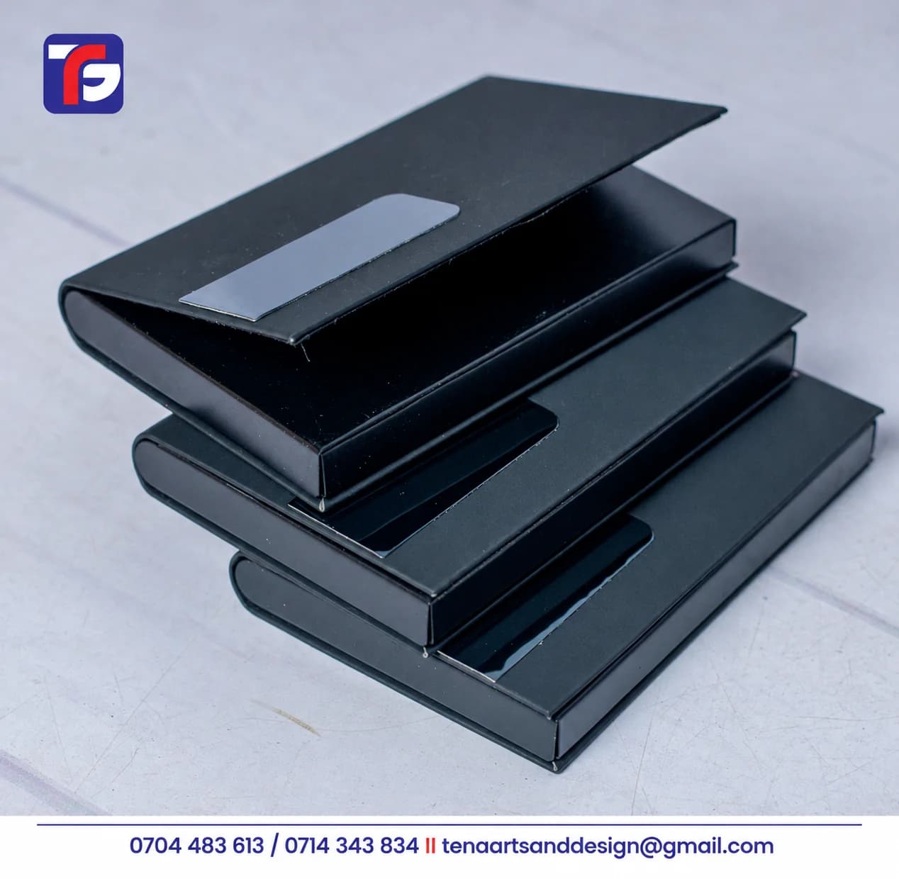Three black flip cover business card holders stacked with the top holder’s lid partly open