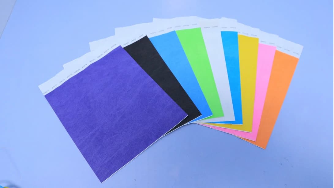 Purple, black, blue, green, white, yellow, pink and orange wristband sheets arranged in a fan